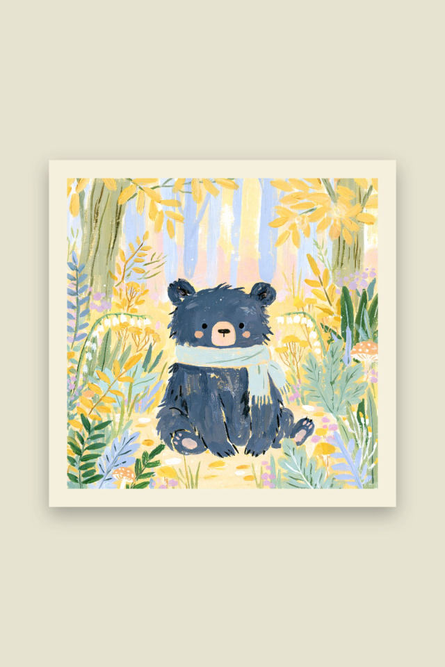 A dark navy baby bear wearing a pale mint scarf sits on a sunlit forest path among yellow blooms, ferns and tiny mushrooms, on a cream border